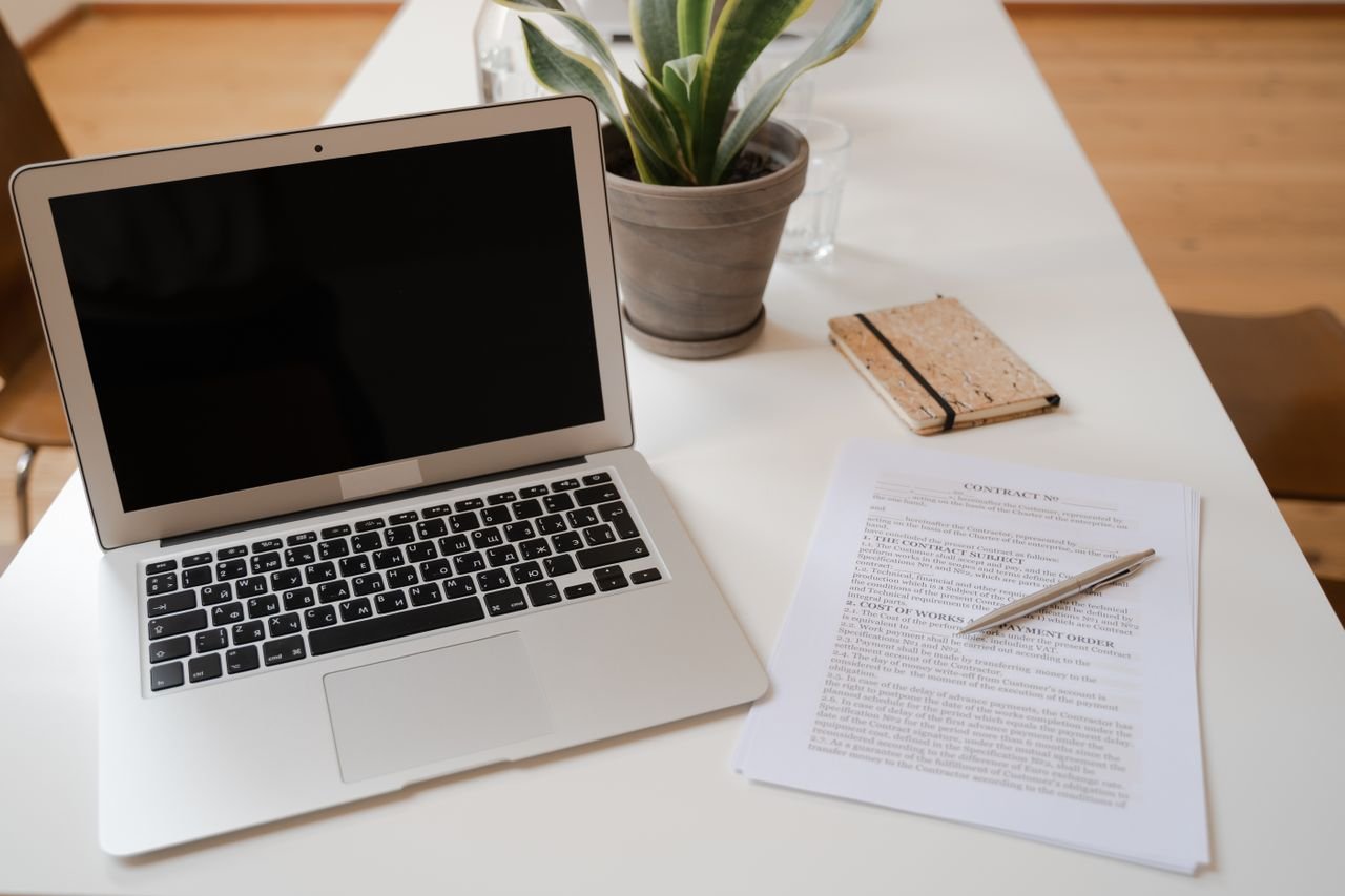 Service business owner reviewing quotes and invoices on a laptop and smartphone