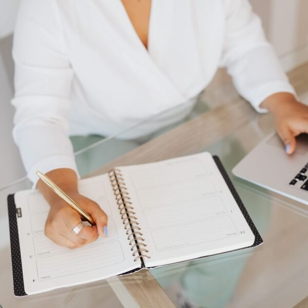 Small business owner reviewing a printed task list beside a laptop while prioritizing work