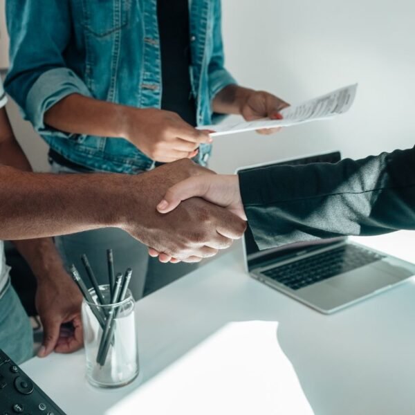 Business owner welcoming a new client at a desk with a laptop