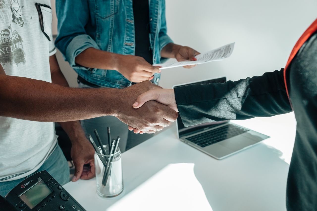 Business owner welcoming a new client at a desk with a laptop