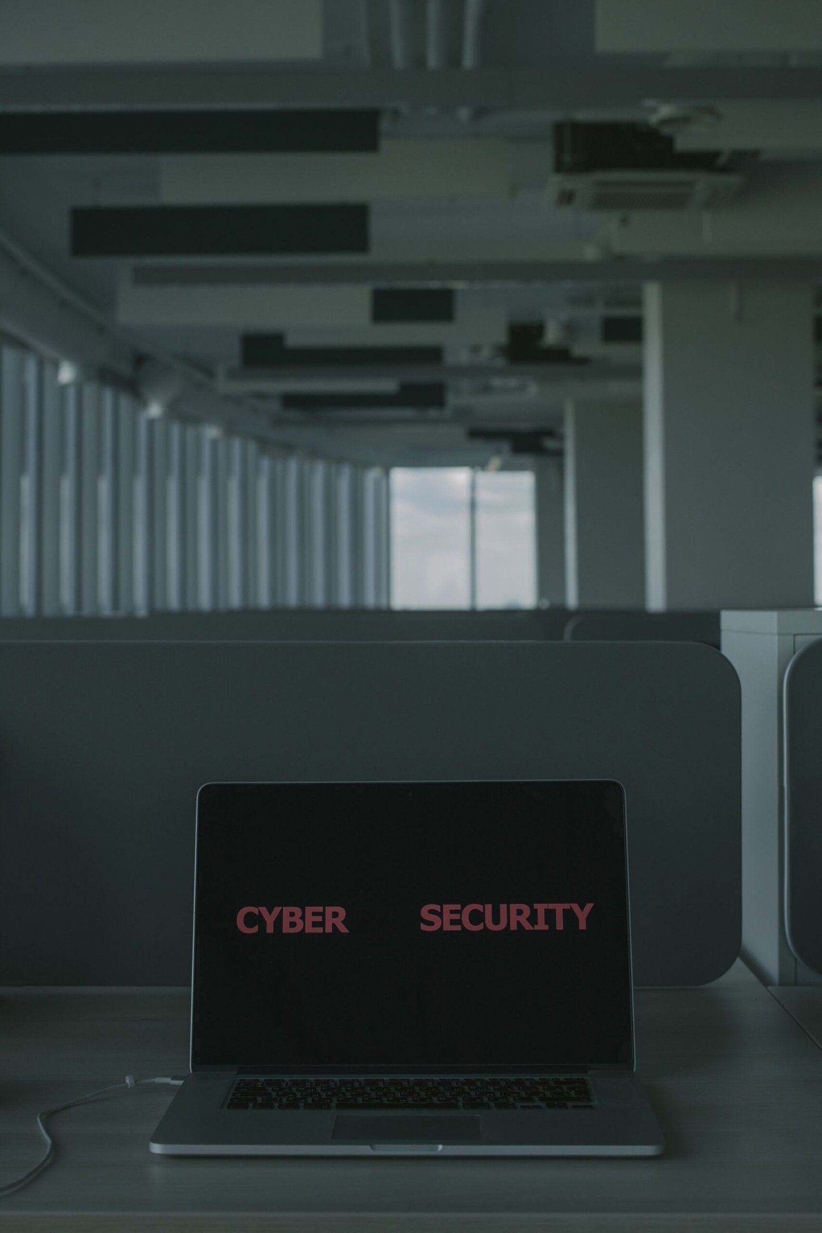 A laptop displaying the words Cyber Security on its screen in a modern office setting