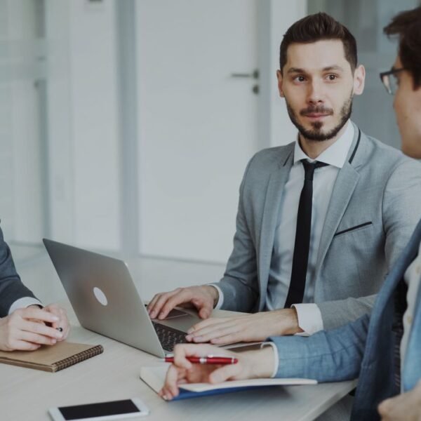 A small business owner reviews an automation project proposal with a consultant at a laptop in an office setting