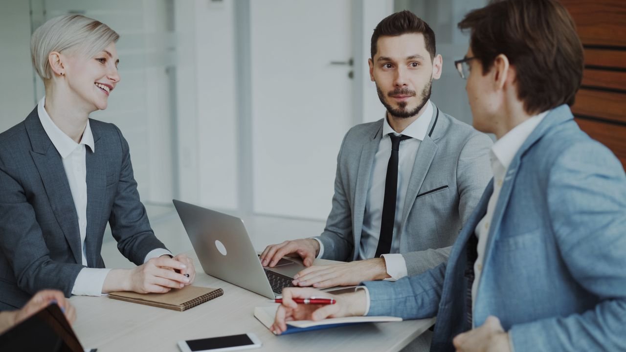 A small business owner reviews an automation project proposal with a consultant at a laptop in an office setting