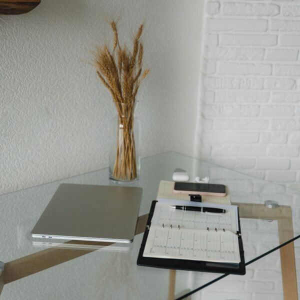 A laptop, planner, and pen on a clean desk, ready for workflow planning