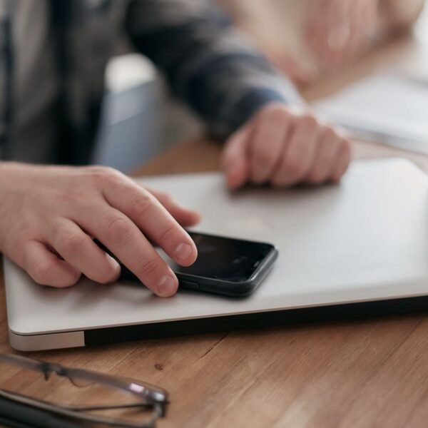 A professional working at a minimalist desk with a laptop, papers, and a lamp. AI automation.